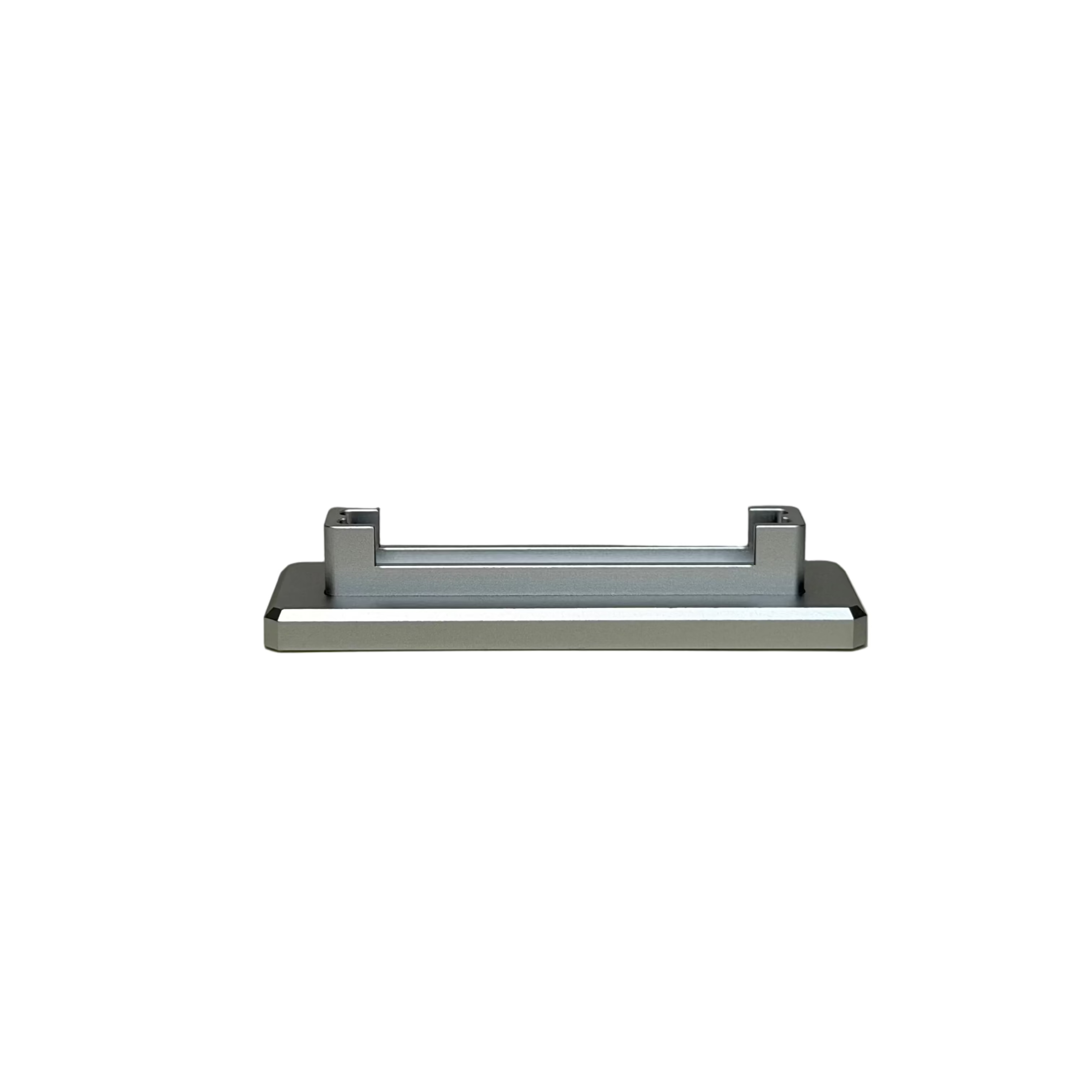 A modern rectangular wall-mounted sink drain with a brushed silver metal finish, mounted on a round, off-white ceramic plinth against a textured beige wall.