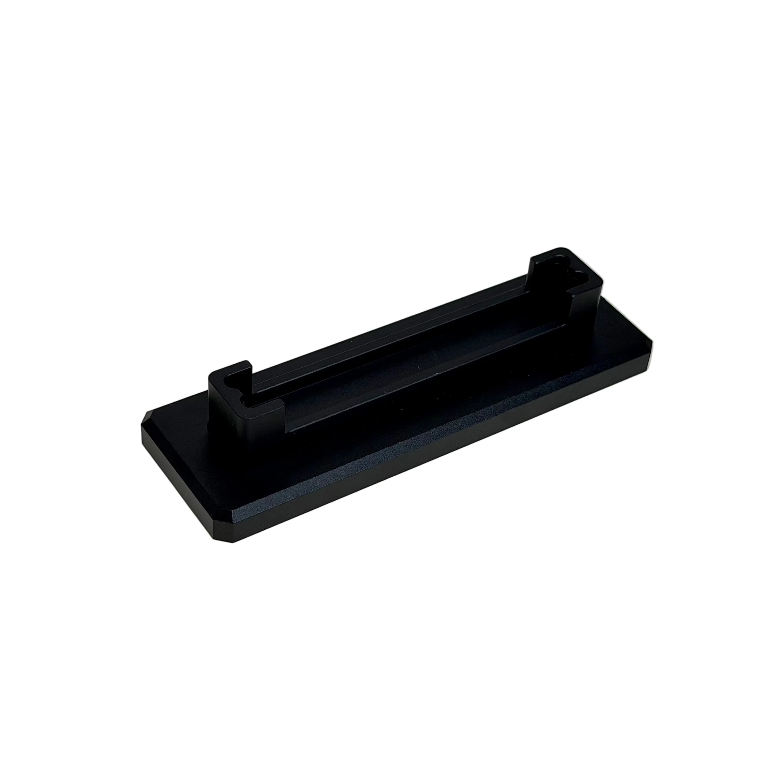 A black rectangular metal stand or clip with a central slot, resting on a round off-white display stand.