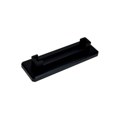 A black rectangular metal stand or clip with a central slot, resting on a round off-white display stand.