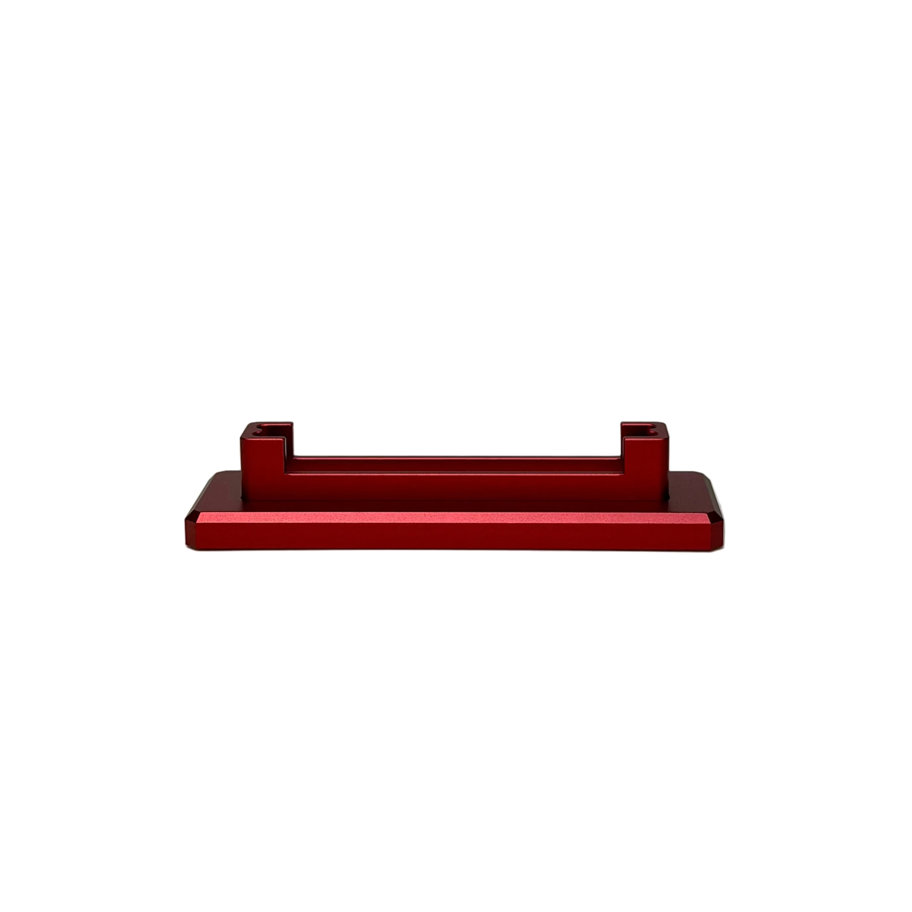 A small red anodized metal bracket or clip with two vertical tabs, displayed on a round white turntable against a textured light gray background.