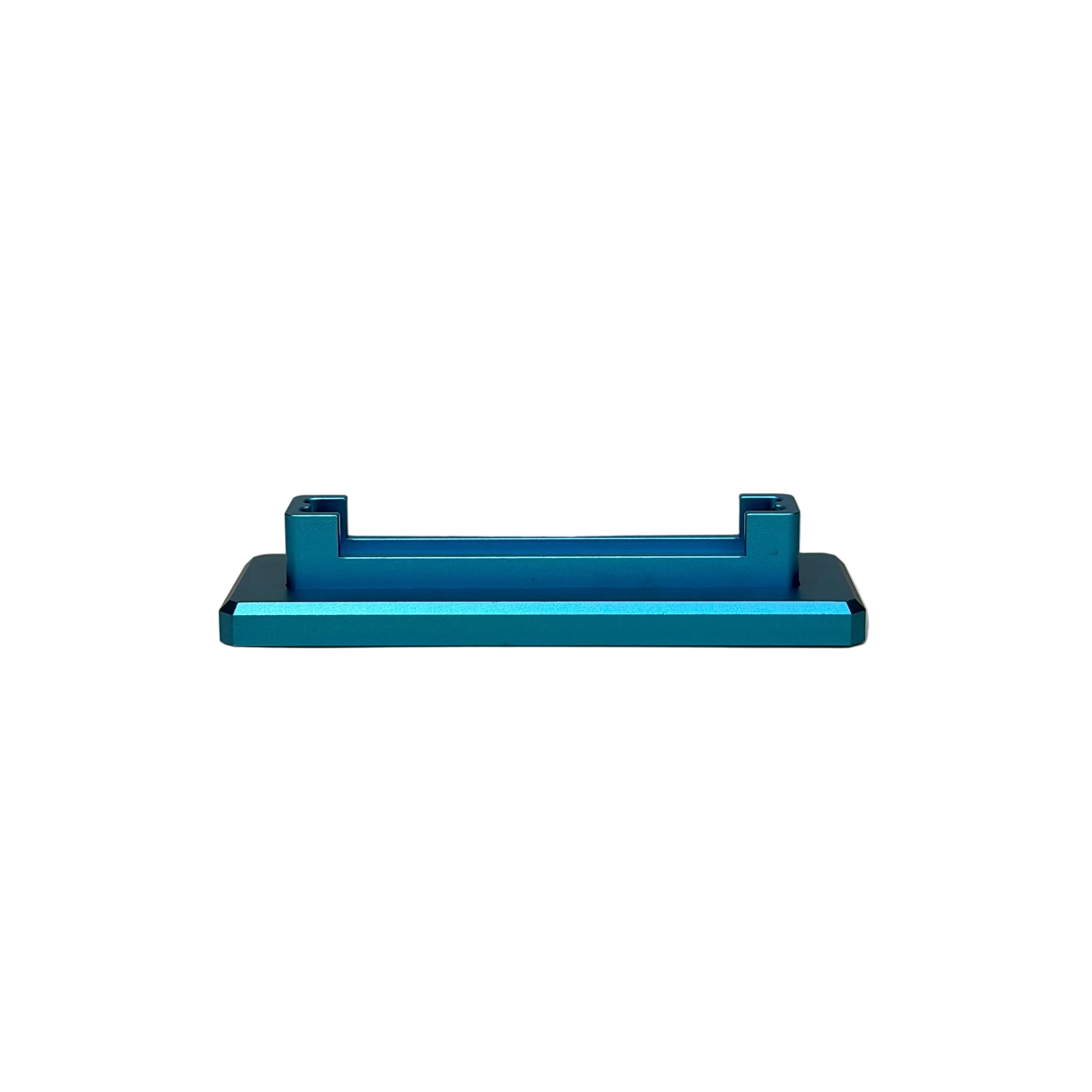 A metallic teal anodized aluminum handlebar clamp or bracket, displayed on a round beige pedestal against a textured beige wall.