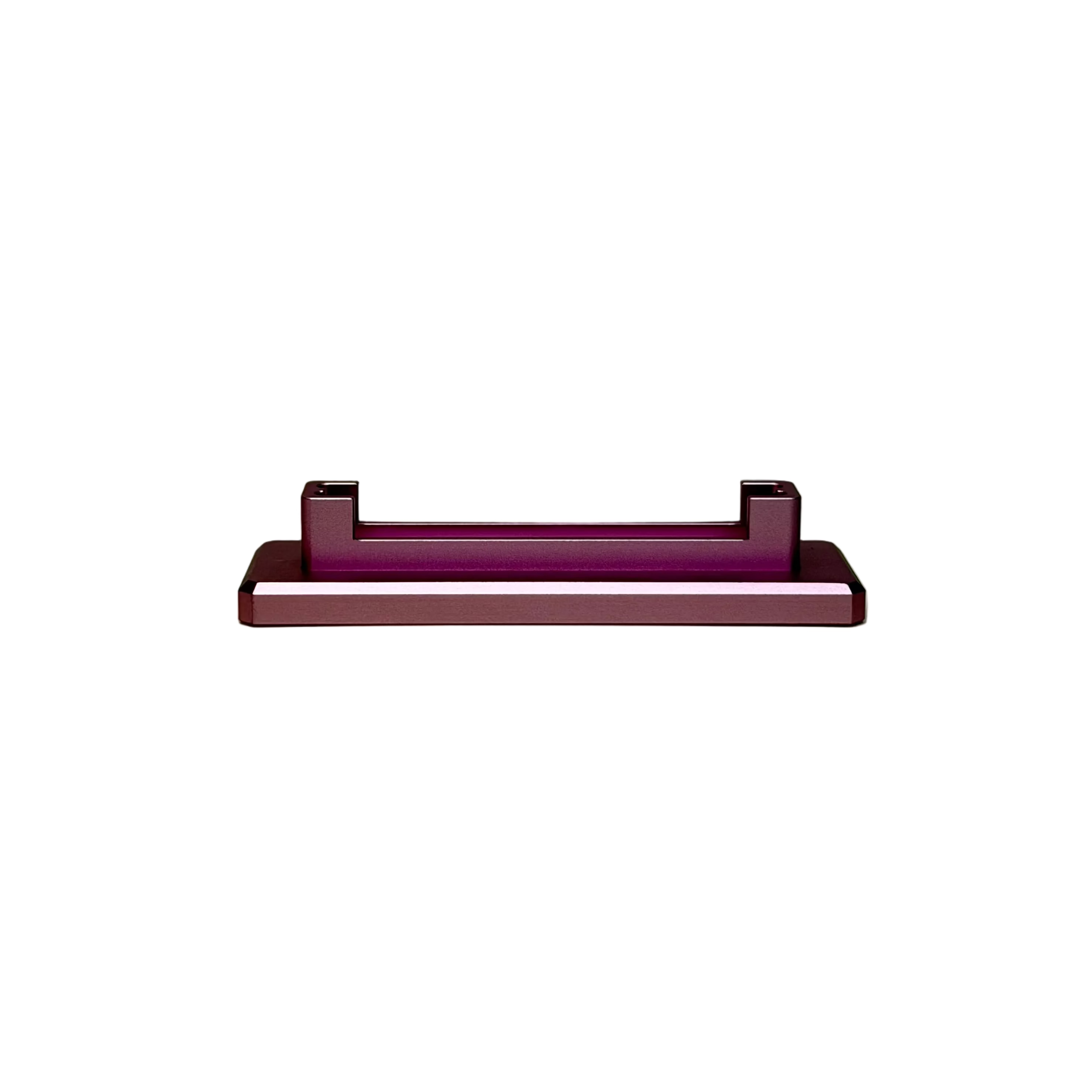 A small rectangular pink metal component with a white stripe, displayed on a round cream-colored platform against a textured light gray background.
