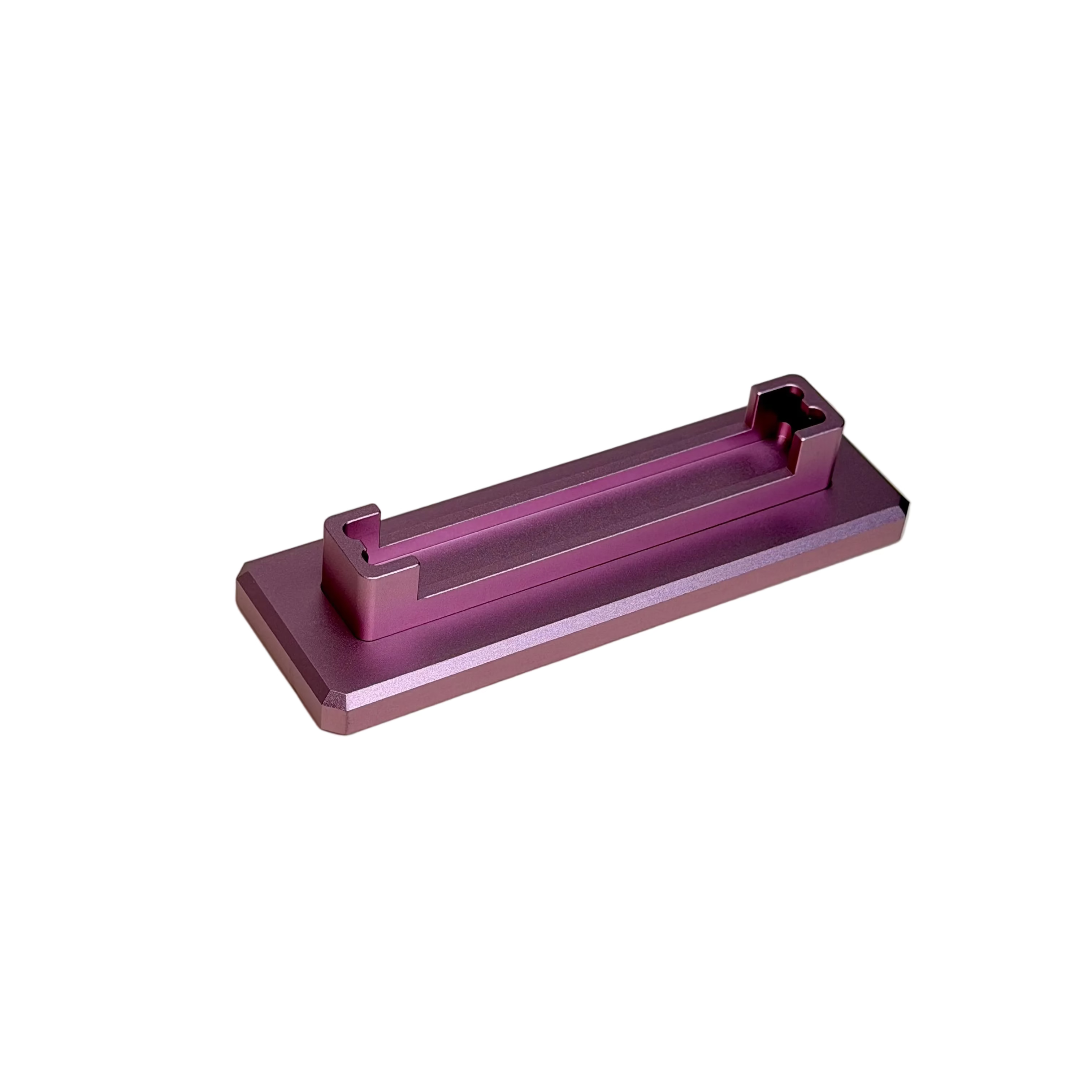 A small metallic pink rectangular component with a raised channel, shown on a round cream display stand against a white surface.